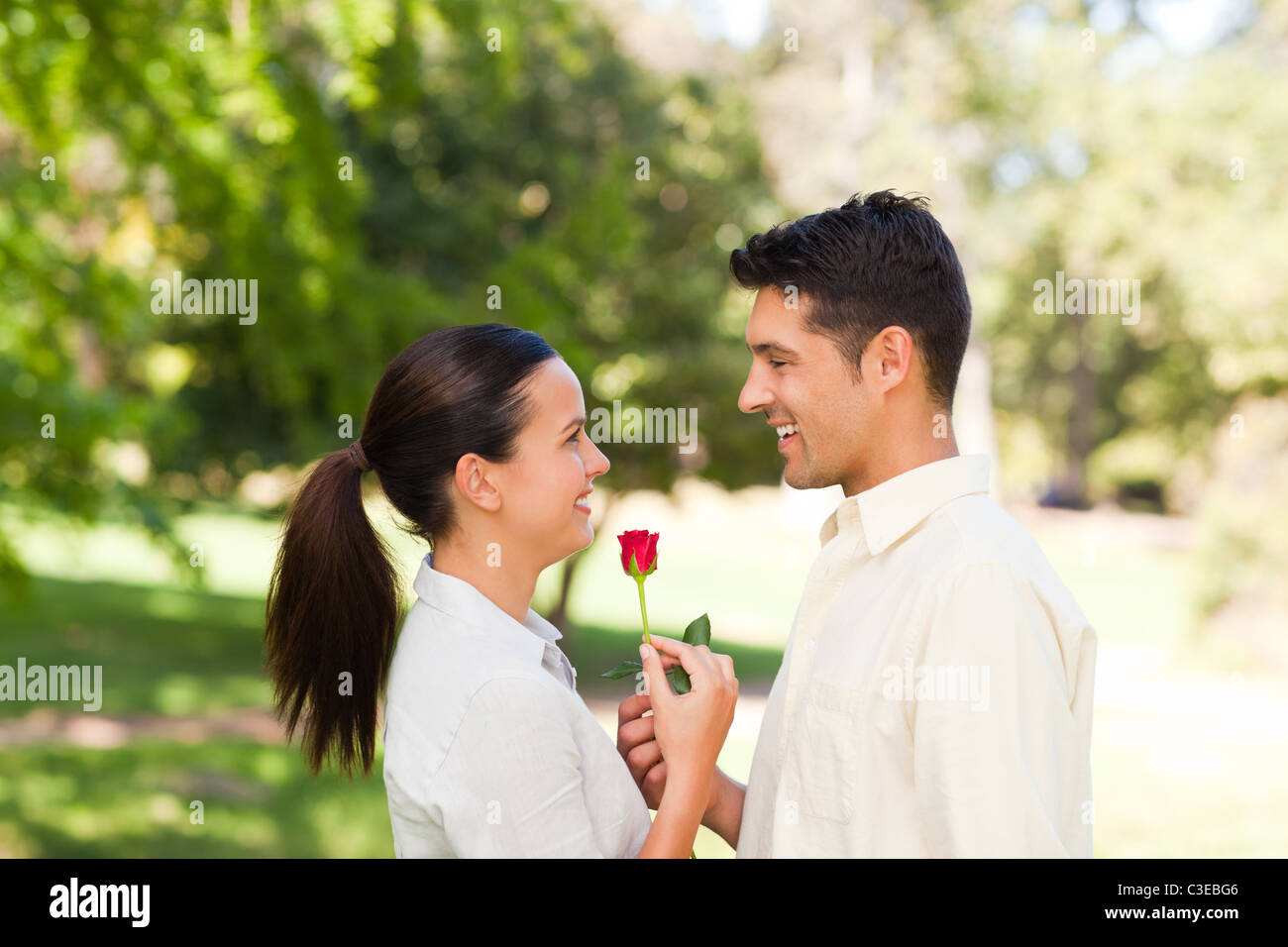 Felice l'uomo che offre una rosa alla sua ragazza Foto Stock