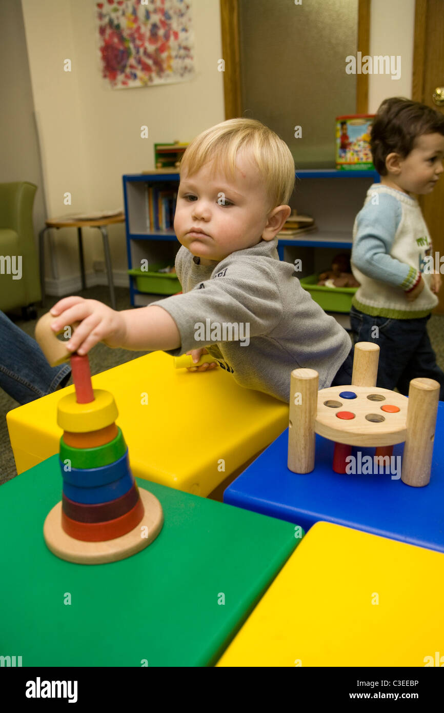 Scuola materna bambino sviluppa mano coordinazione occhio attraverso la riproduzione con tipo puzzle giocattoli. Foto Stock