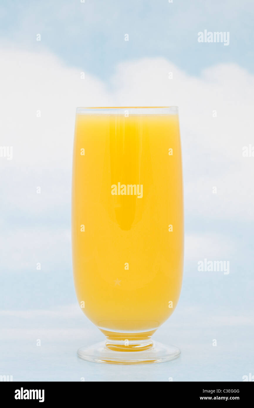 Un bicchiere di succo d'arancia fresco contenente vitamina C contro il cielo blu sullo sfondo. Foto Stock