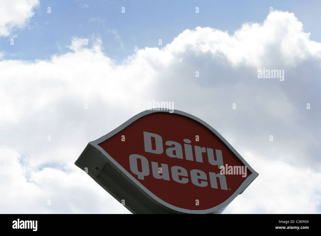 Dairy Queen segno si erge verso il cielo con alcuni pigri, estivo, bianco puffy midwestern nuvole come sfondo. Foto Stock