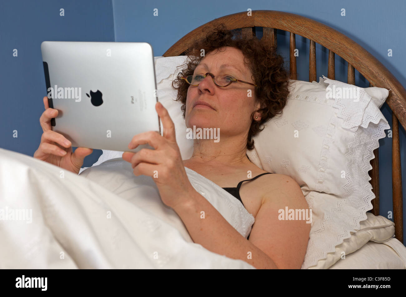La donna la lettura di un libro su un iPad di Apple computer tablet Foto Stock