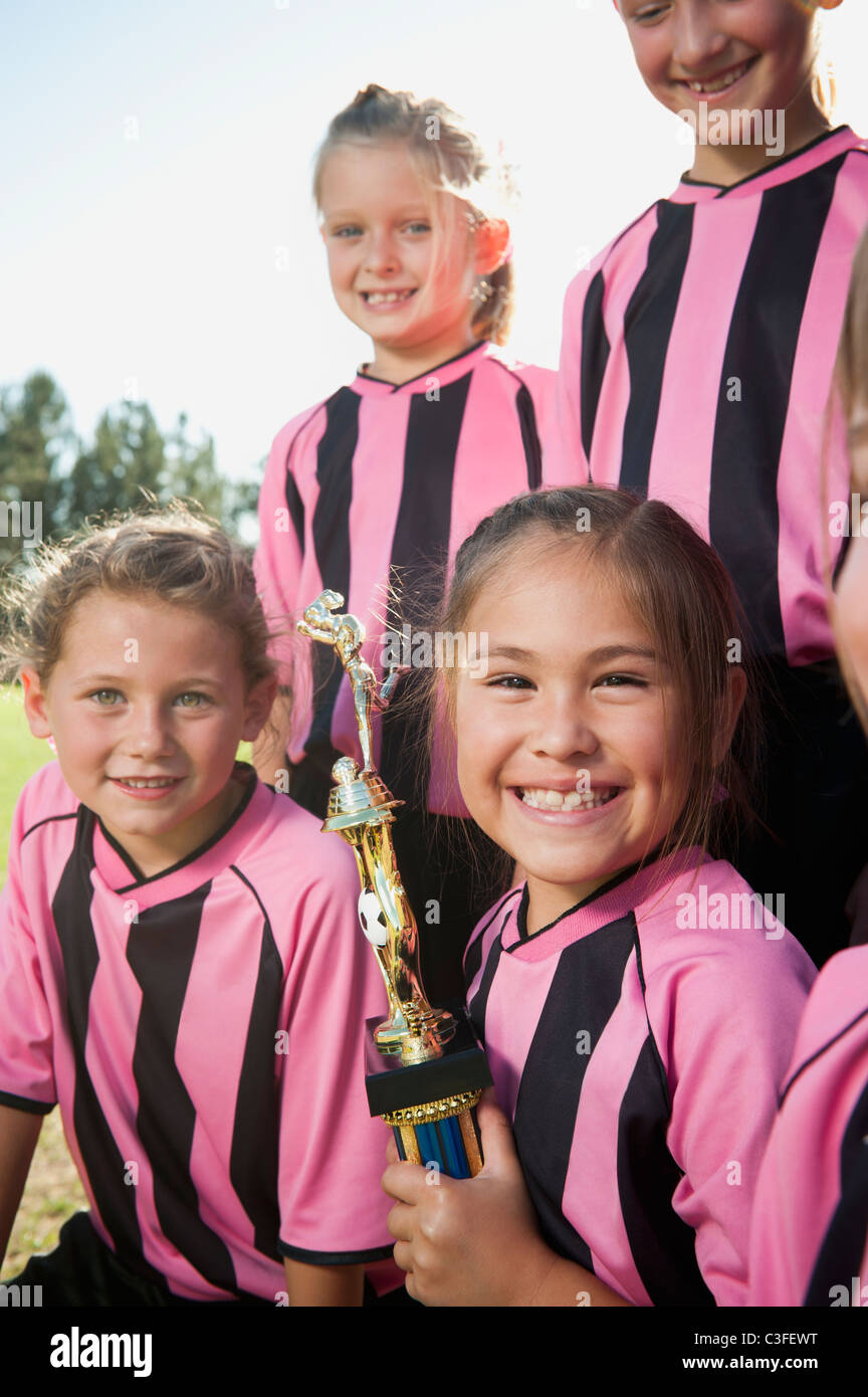 Ragazza sorridente i giocatori di calcio in posa con il trofeo Foto Stock