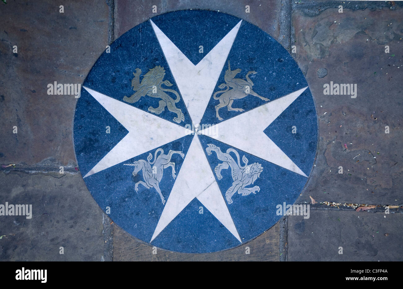 Il logo per l'ordine di San Giovanni / Saint John Ambulance nella pavimentazione al di fuori di San Giovanni Gate, St John's Lane, Londra. Regno Unito. Foto Stock