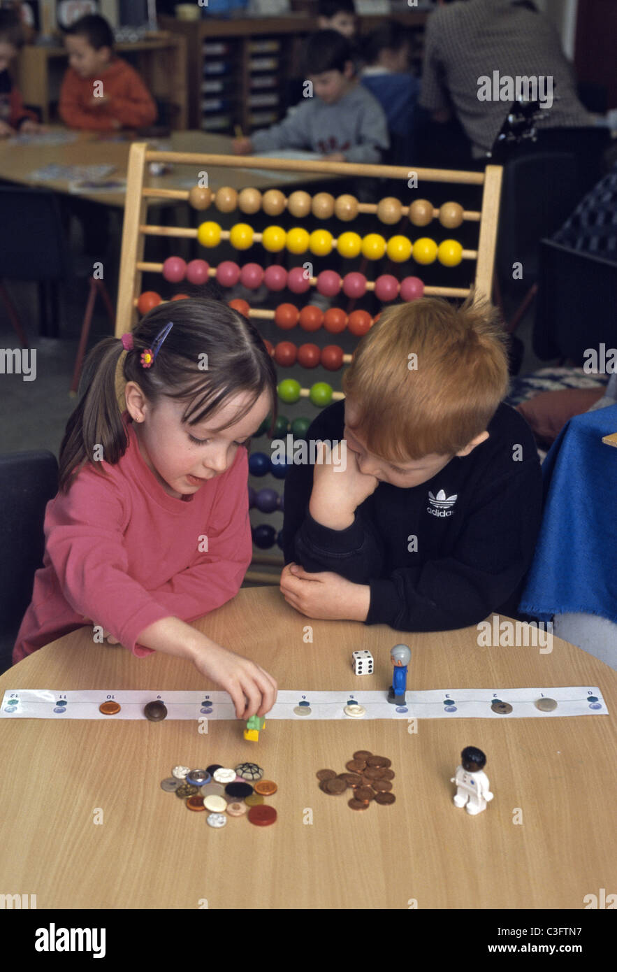 Due bambini nella scuola primaria di lavorare con pochi spiccioli e l apprendimento dei pulsanti per aggiungere e sottrarre Foto Stock