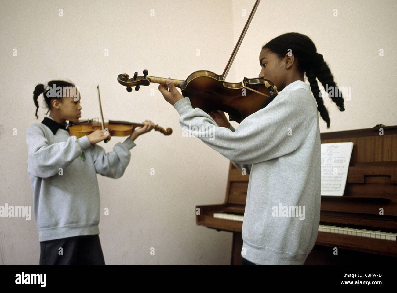 Due scuola secondaria ragazze suona il violino nella classe di musica Foto Stock