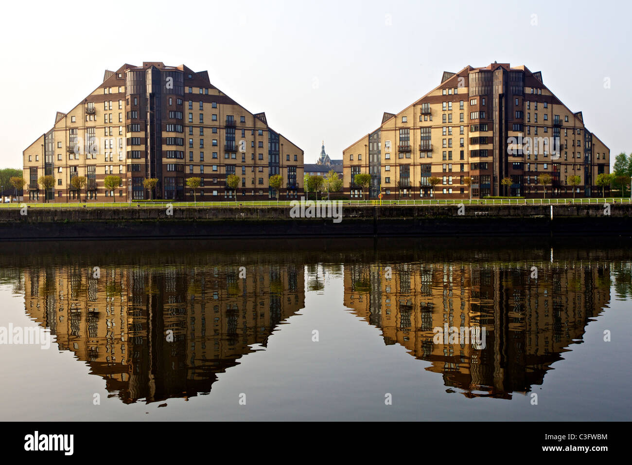 Moderno appartamento blocchi riflessa nel tranquillo Fiume Clyde con un minuscolo Govan Angelo visibile tra di loro, Glasgow, Scotland, Regno Unito Foto Stock