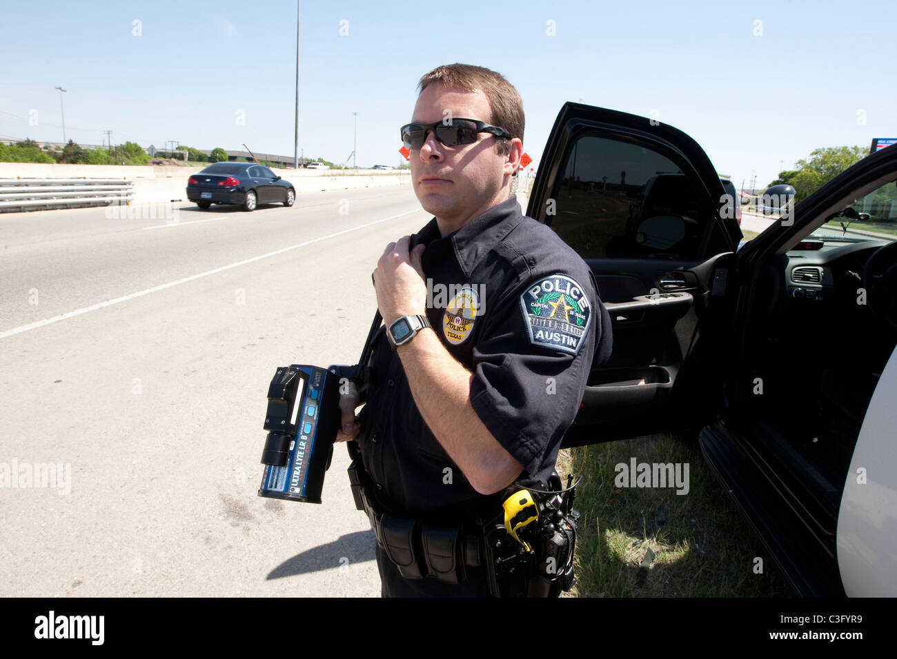 Maschio di funzionario di polizia utilizza il radar di velocità la pistola per la cattura di velocizzare i driver su autostrada in Austin Texas USA Foto Stock