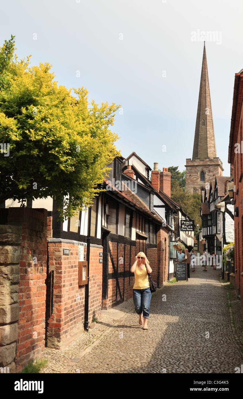 Una donna bionda indossando occhiali da sole cammina verso la telecamera lungo Church Lane in Ledbury, Herefordshire, England, Regno Unito Foto Stock