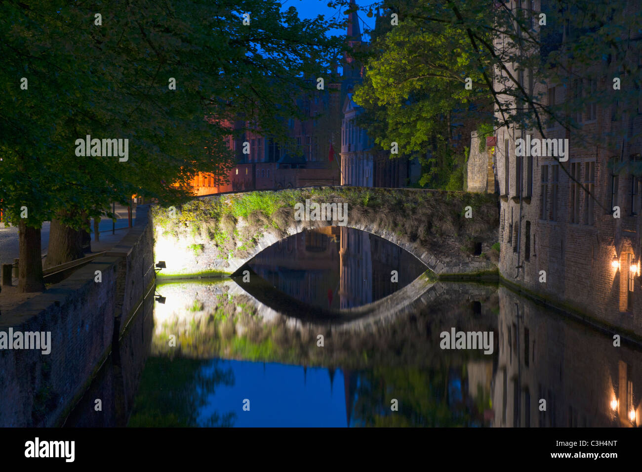 Edifici illuminati e ponte riflettendo in acqua durante la notte, il centro storico di Bruges, Belgio Foto Stock