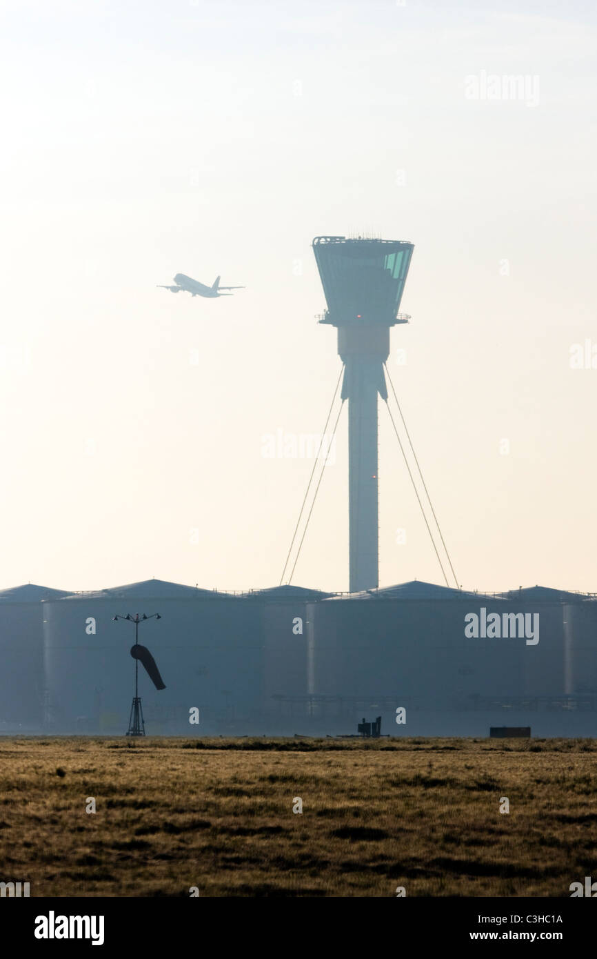 Comercial aereo di linea in decollo e di Londra Heathrow torre di controllo. Foto Stock