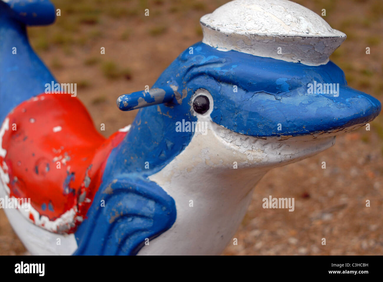 Weathered attrezzature per parchi giochi. Sorridente focena indossando un marinaio della PAC e la sella. Foto Stock