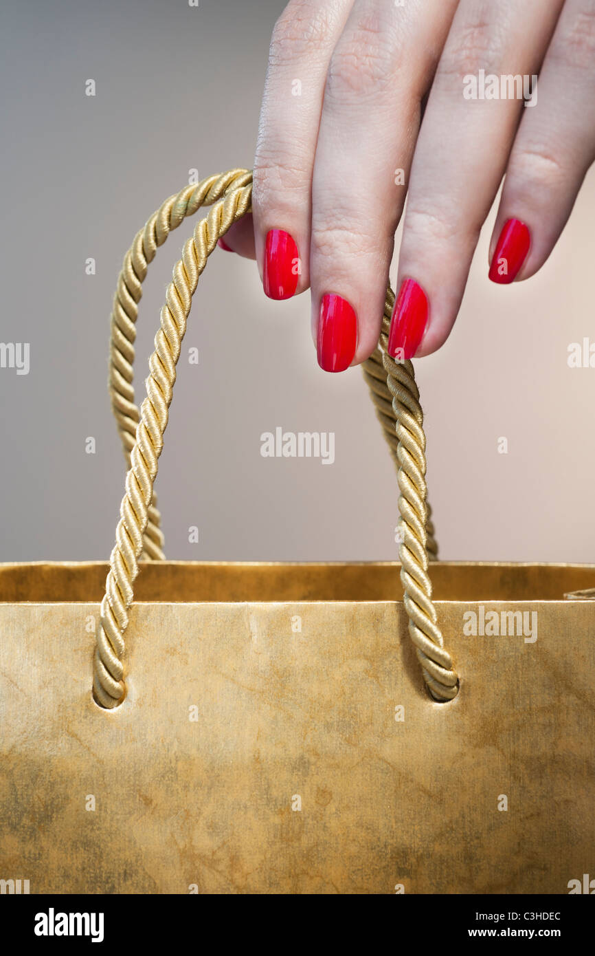 Close up della donna di mano con red Nail Polish stringa tenendo la maniglia del sacco di carta Foto Stock