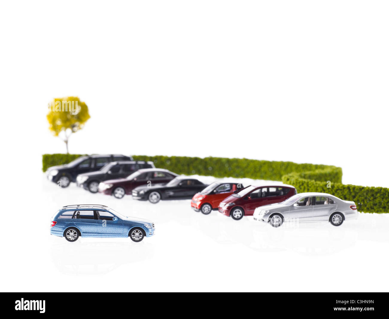 Fila di diverse auto parcheggiate vicino hedge Foto Stock
