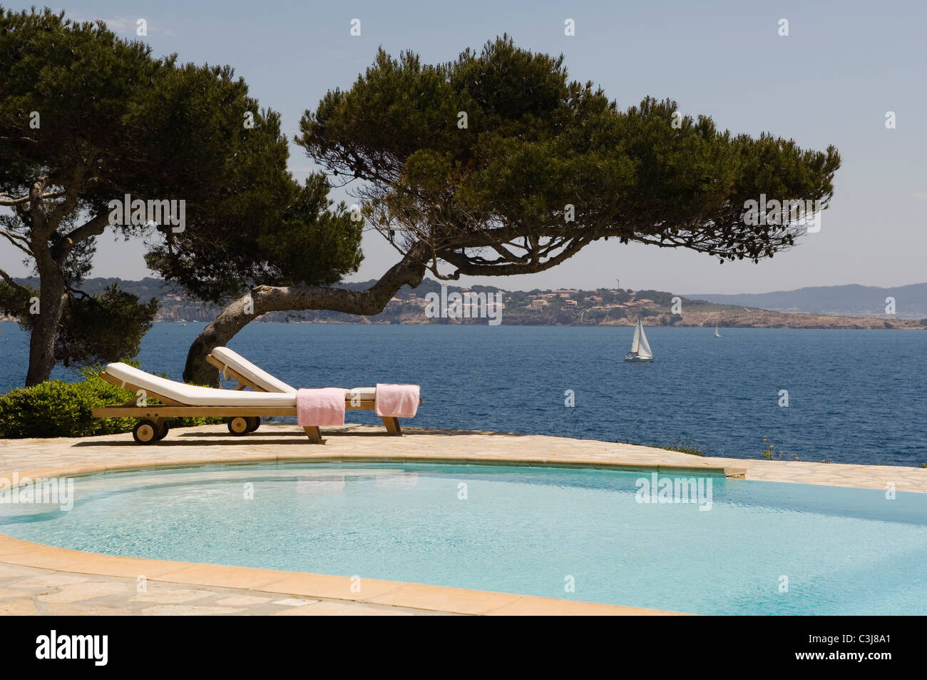 Due lettini per prendere il sole sul lato di una piscina esterna con vedute del Mediterraneo Foto Stock