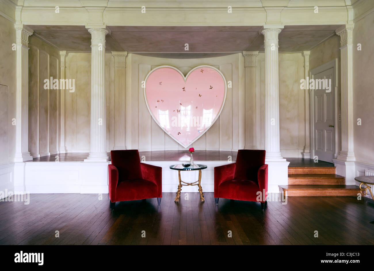 Velluto rosso poltrone in legno di spazio vivente con Damian Hirst a forma di cuore ad opera in background Foto Stock