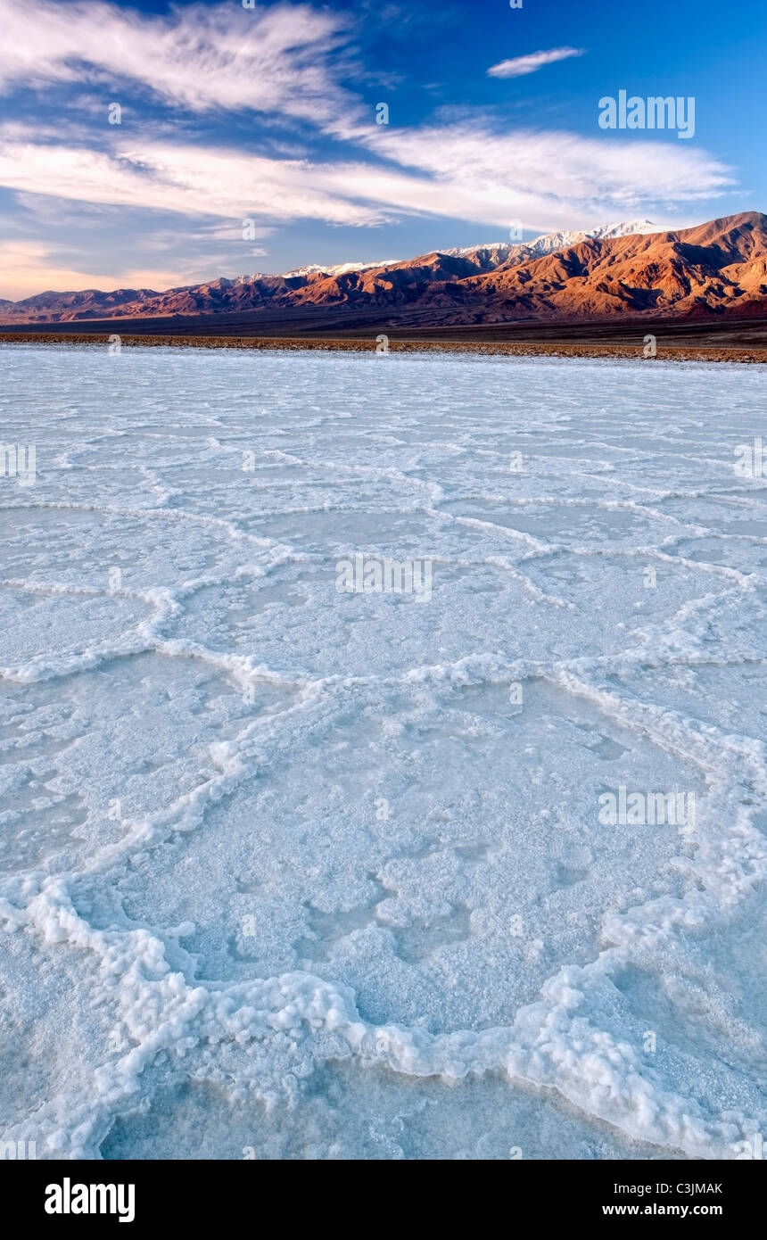 Mattina nuvole sopra il sale poligoni di Badwater Basin con Snow capped telescopio picco in California's Death Valley. Foto Stock