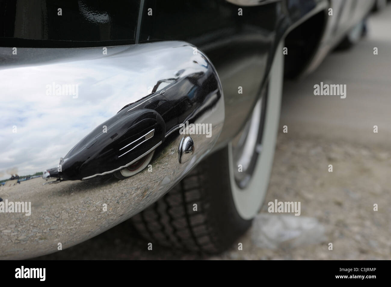 La riflessione di nero oldtimer nel grande paraurti cromato di un altro oldtimer Foto Stock