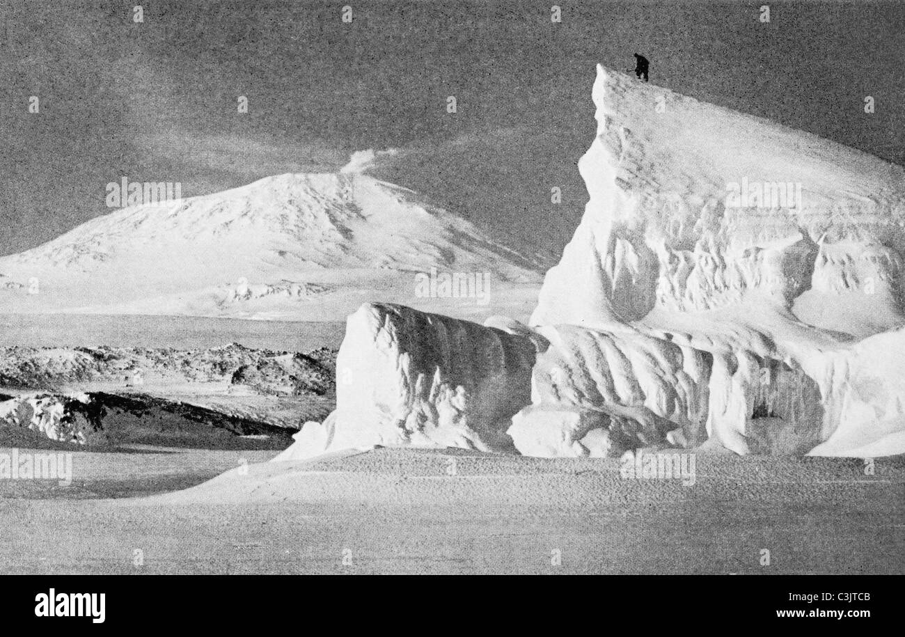 Un membro di Robert Scott Terra Nova Expedition sulla punta di un iceberg in Antartide nel 1911 con il Monte Erebus in background. Foto Stock