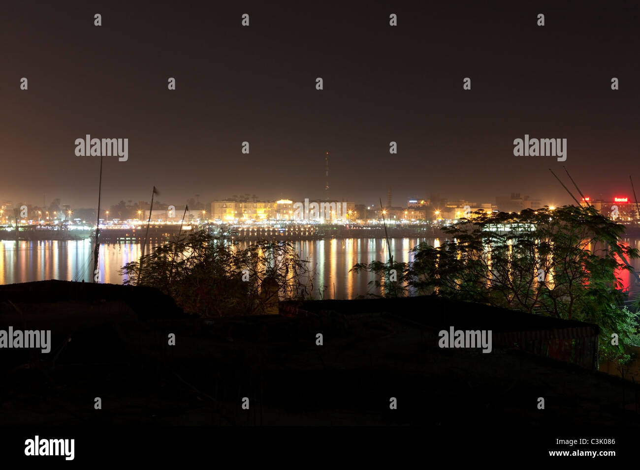 Di notte il colpo da riva occidentale del Fiume Nilo, guardando oltre all'Hotel sulla riva orientale, Luxor, Egitto Foto Stock