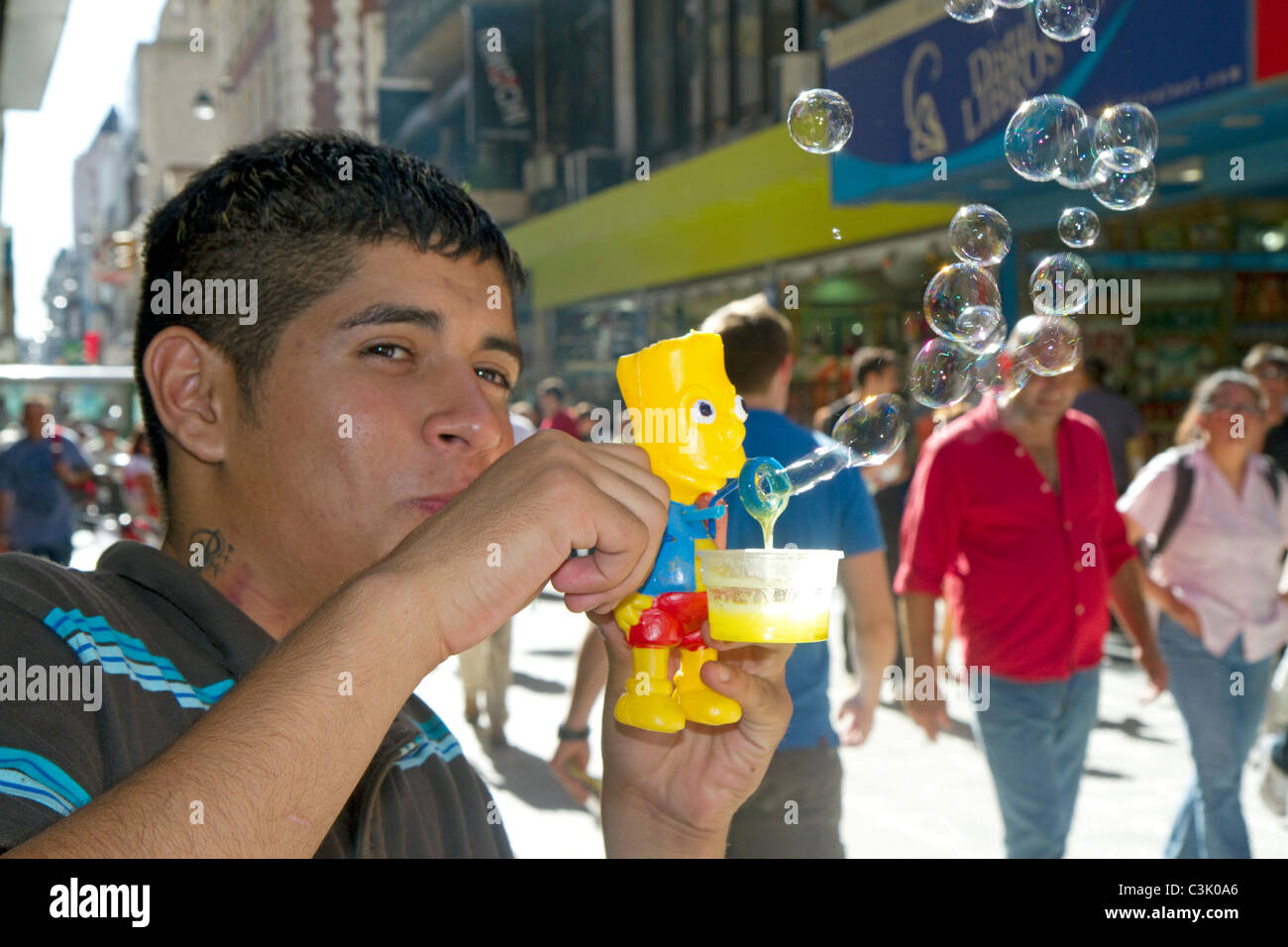 Uomo argentino a soffiare bolle con un Bart Simpson toy lungo la Calle Florida nel Retiro barrio di Buenos Aires, Argentina. Foto Stock