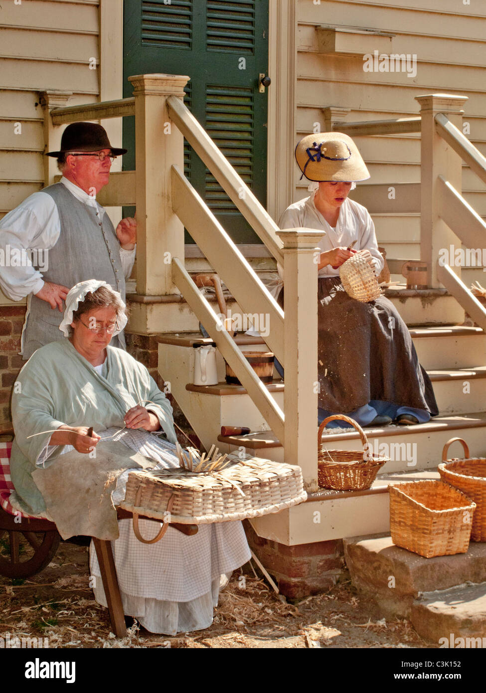 Indossando costumi storici, reenactors dimostrare il cestello storico-competenze di tessitura di Colonial Williamsburg, VA. Foto Stock