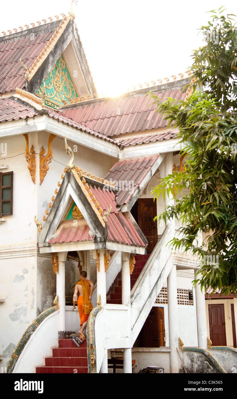Un monaco in arancione vesti passeggiate su per le scale di Wat Xian Nyeun, tempio buddista, Vientiane, Laos Foto Stock