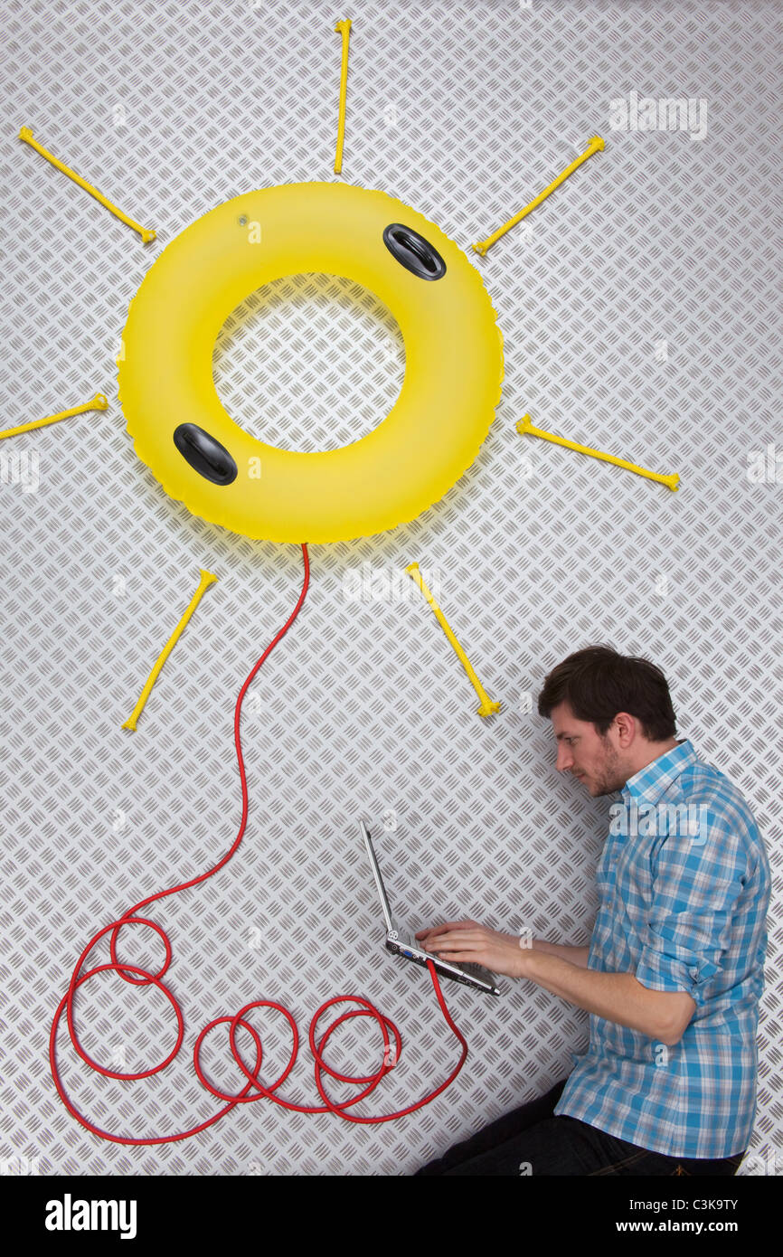 Metà uomo adulto utilizzando laptop collegato a sun galleggiante di forma Foto Stock