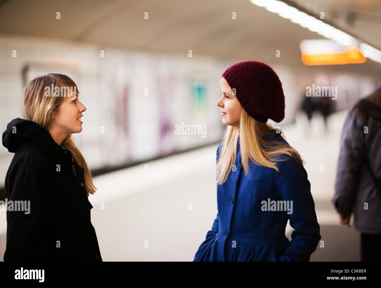 Le ragazze adolescenti (14-15) la conversazione sulla piattaforma ferroviaria Foto Stock