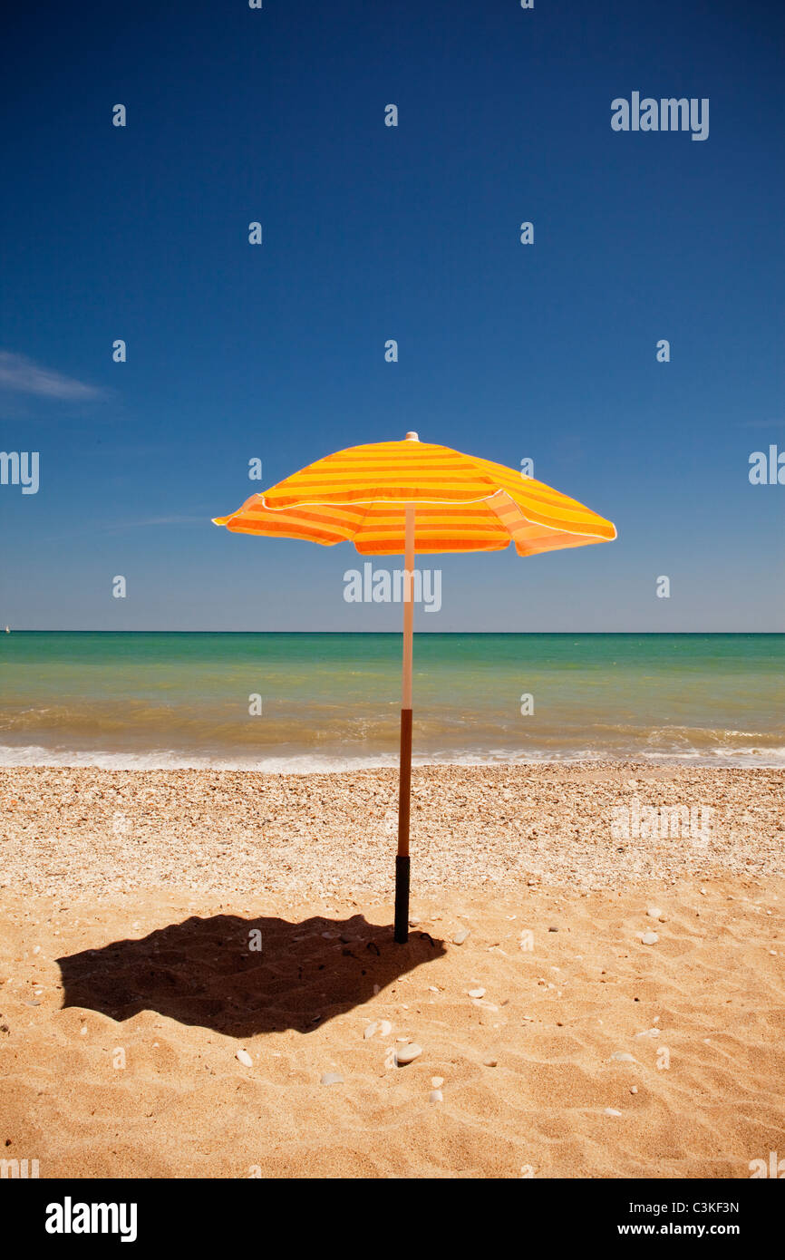 Ombrellone giallo ombra di colata sulla spiaggia Foto Stock