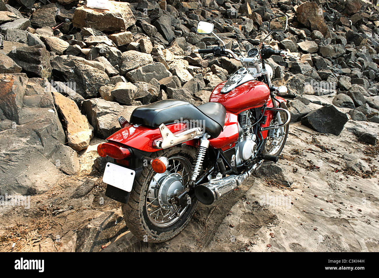 Red motorcylce spiaggia sabbiosa terrapieno roccioso paesaggio spazio di copia Foto Stock