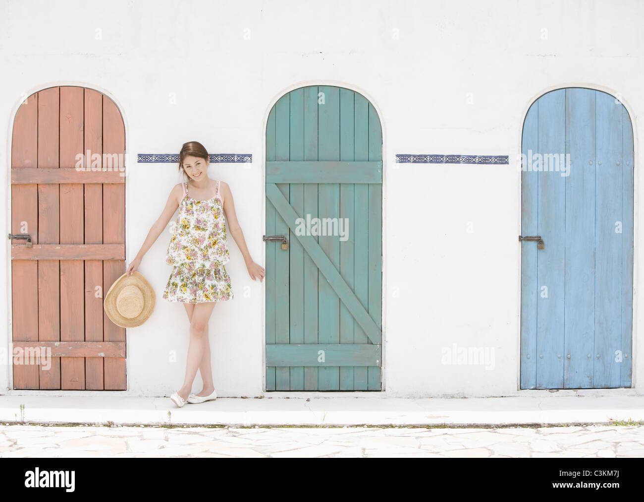 Giovane donna in piedi di fronte a porte Foto Stock