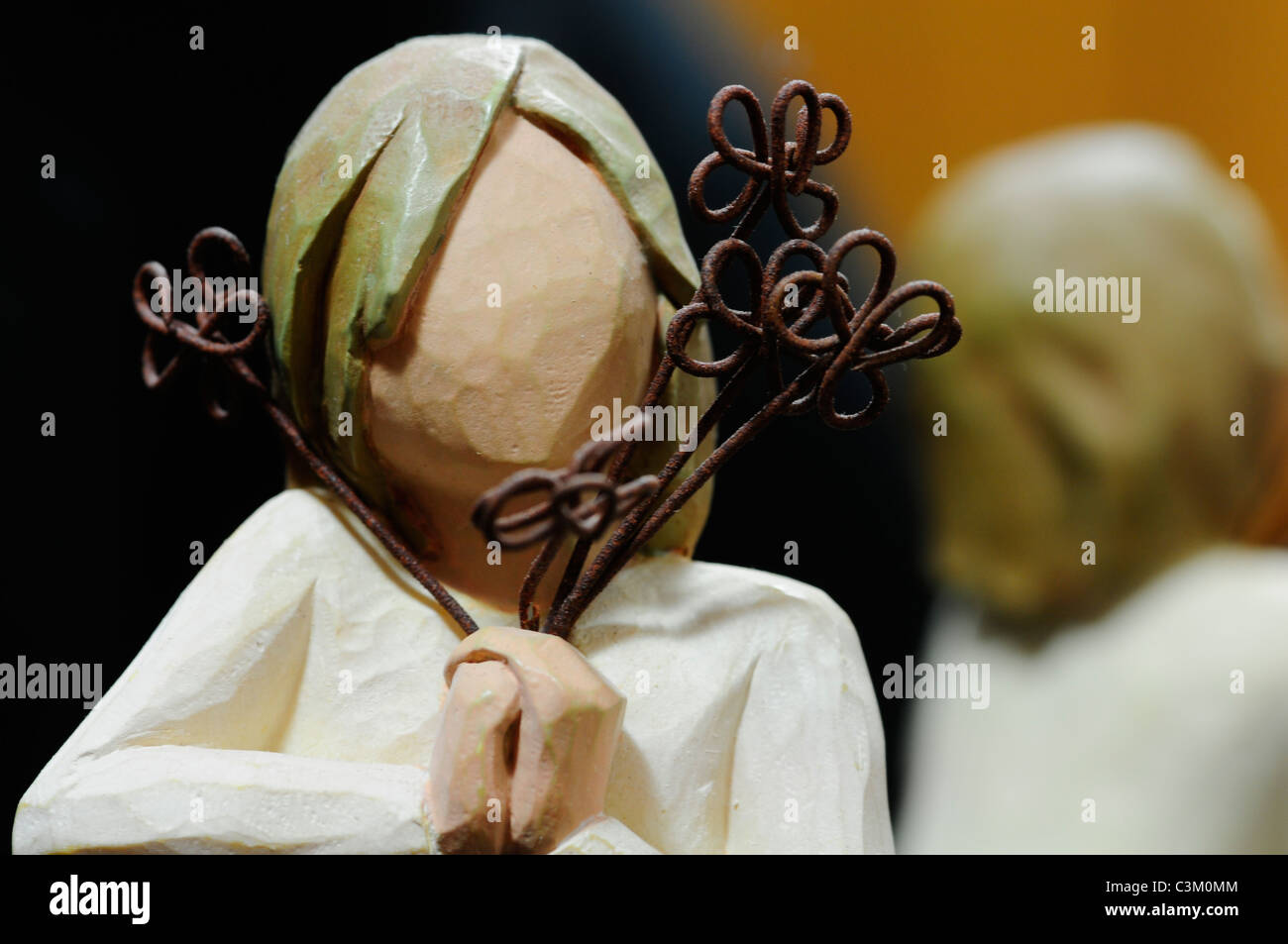 Una scultura in legno di una ragazza senza volto, posizionata verso la telecamera con un sfocata riflesso della sua schiena in background. Foto Stock