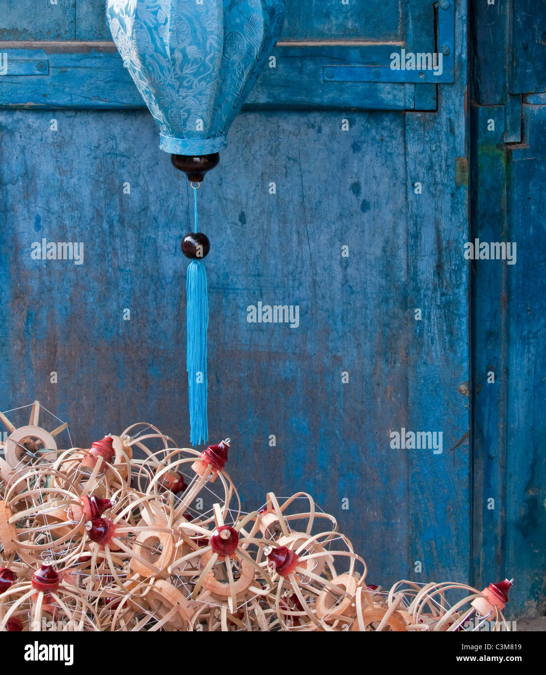 Seta blu e lanterna lanterna di bambù telai contro un blu porta di legno, Hoi An, Viet Nam Foto Stock