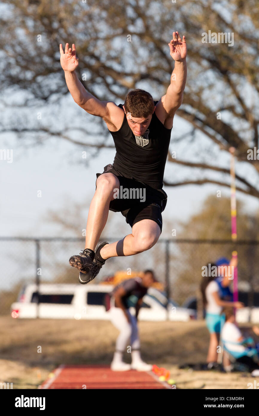 Teenage Anglo atleta maschio salta durante un salto in lungo la concorrenza in Texas Foto Stock
