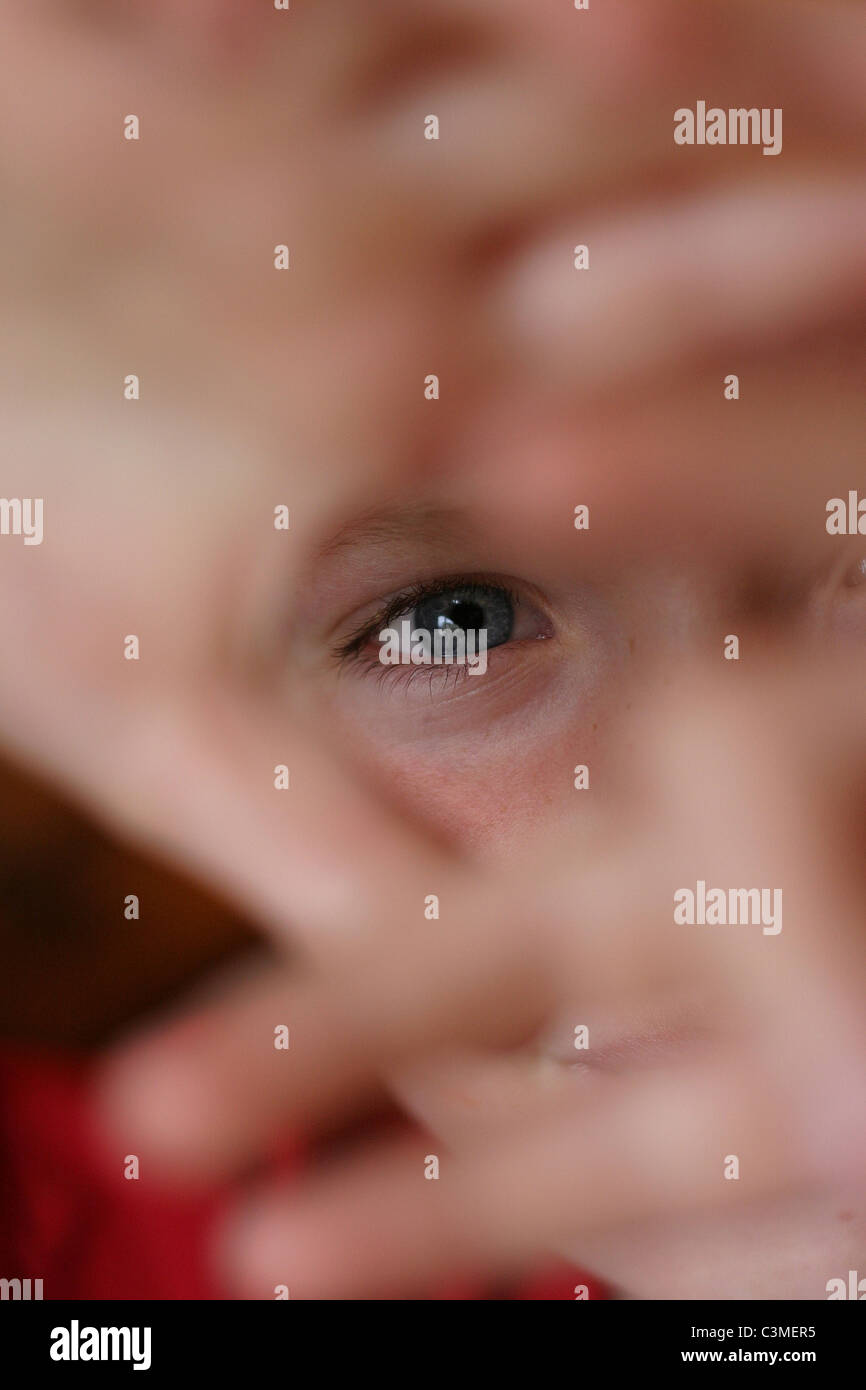 Ragazzo cerca attraverso un foro realizzato il mio le sue due mani. Profondità di campo, ha centrato il suo occhio azzurro. Foto Stock