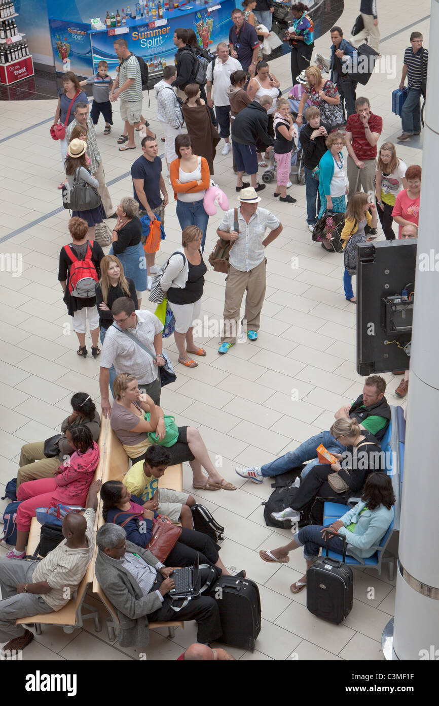 I passeggeri in attesa di informazioni di volo presso la sala partenze del terminal sud dell'aeroporto di Gatwick, Inghilterra Foto Stock