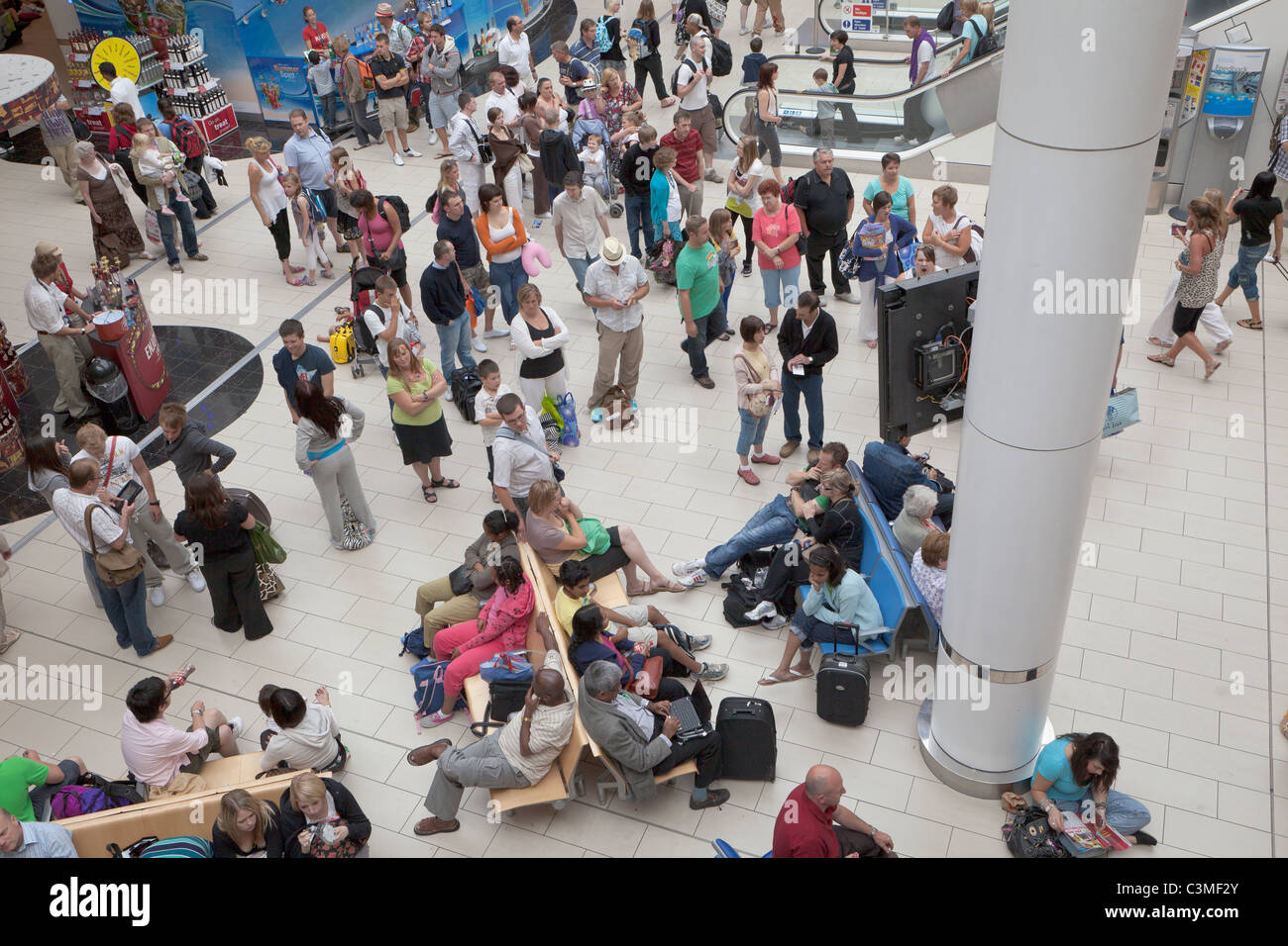 I passeggeri in attesa di informazioni di volo presso la sala partenze del terminal sud dell'aeroporto di Gatwick, Inghilterra Foto Stock