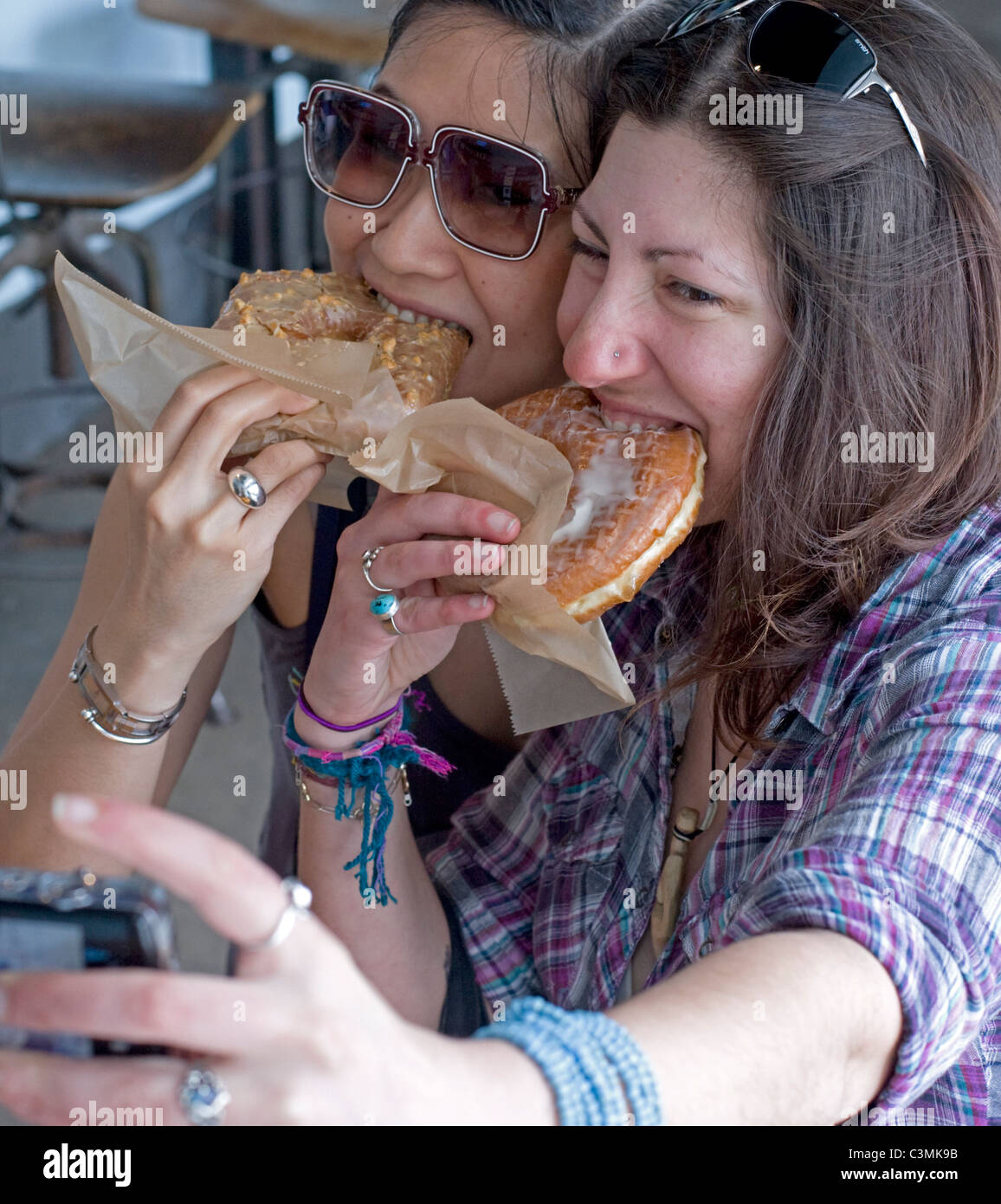 2 donne catturare il momento di mangiare pasta fresca-dadi in New York City. Foto Stock