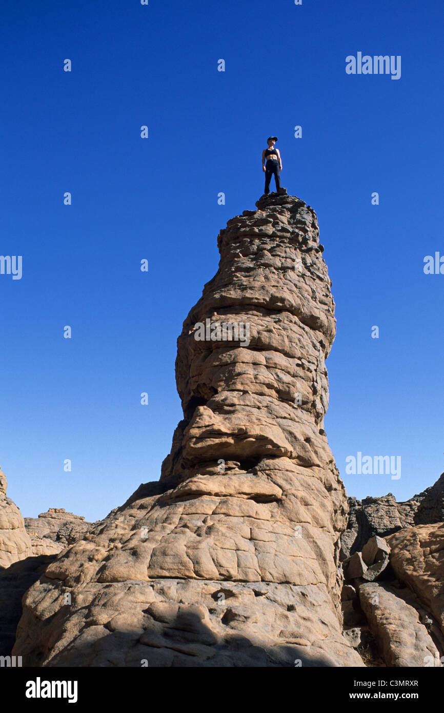 Algeria, Djanet. Deserto del Sahara. Parco Nazionale del Tassili n'Ajjer. Tourist, donna in piedi sulla sommità della roccia. Foto Stock