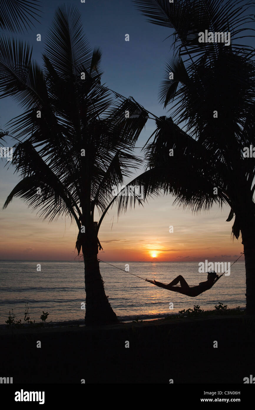 Indonesia, isola di Bali, vicino al villaggio di Tejakula, Gaia Oasis Resort. Le donne, turistico, rilassante in amaca a sunrise. Foto Stock
