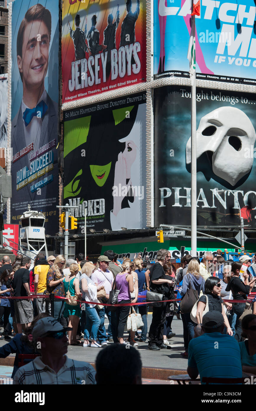 Pubblicità per gli spettacoli di Broadway e la linea per TKTS metà-prezzo biglietti è visto in Times Square a New York Foto Stock