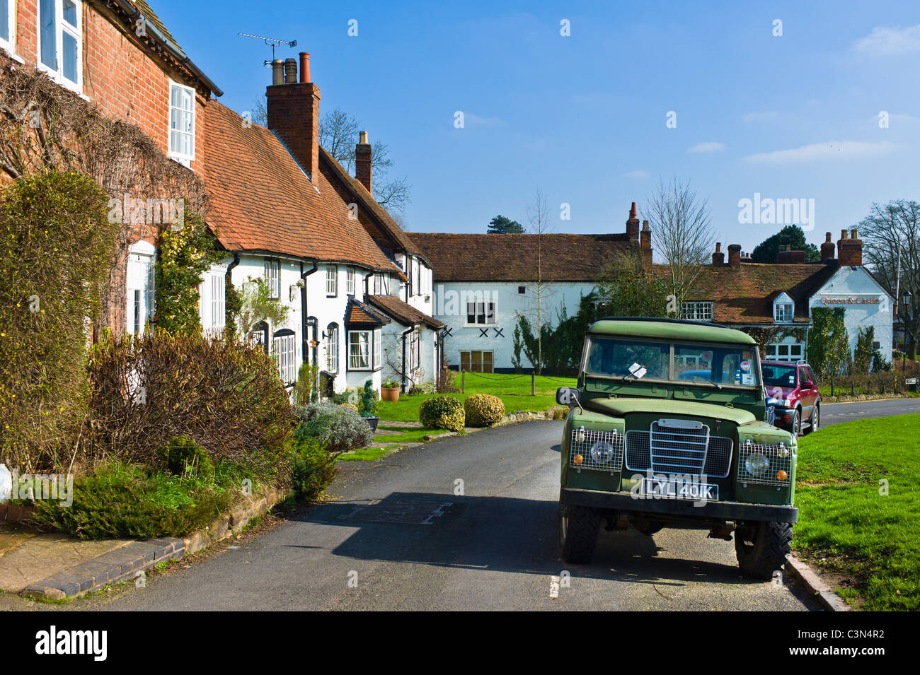 Il vecchio Land Rover parcheggiato di fronte alla tradizionale cottage inglese Foto Stock