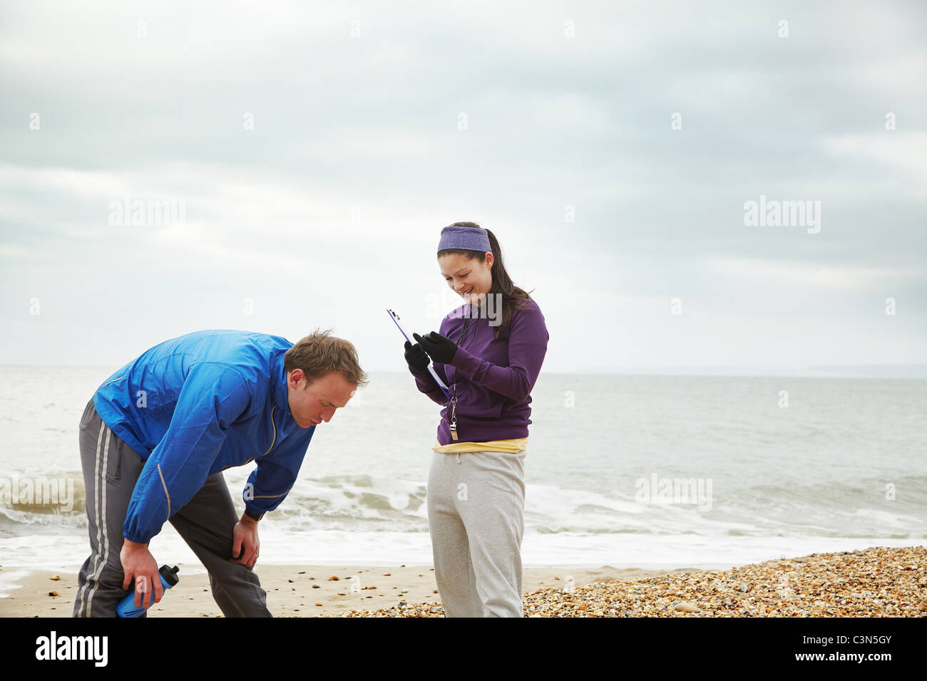 Istruttore di Fitness con l uomo sulla spiaggia Foto Stock