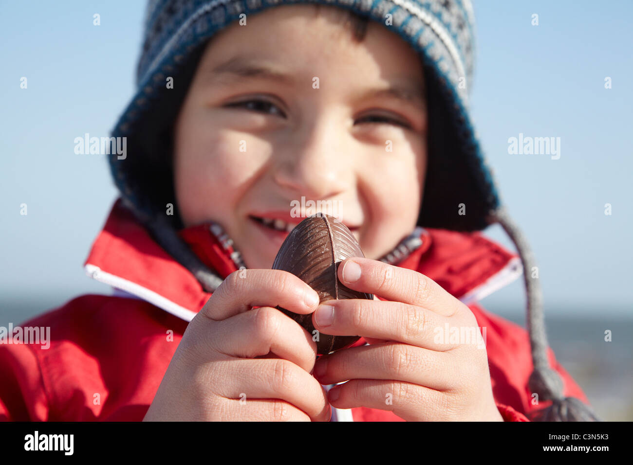 Ragazzo sorridente con uovo di cioccolato al di fuori Foto Stock