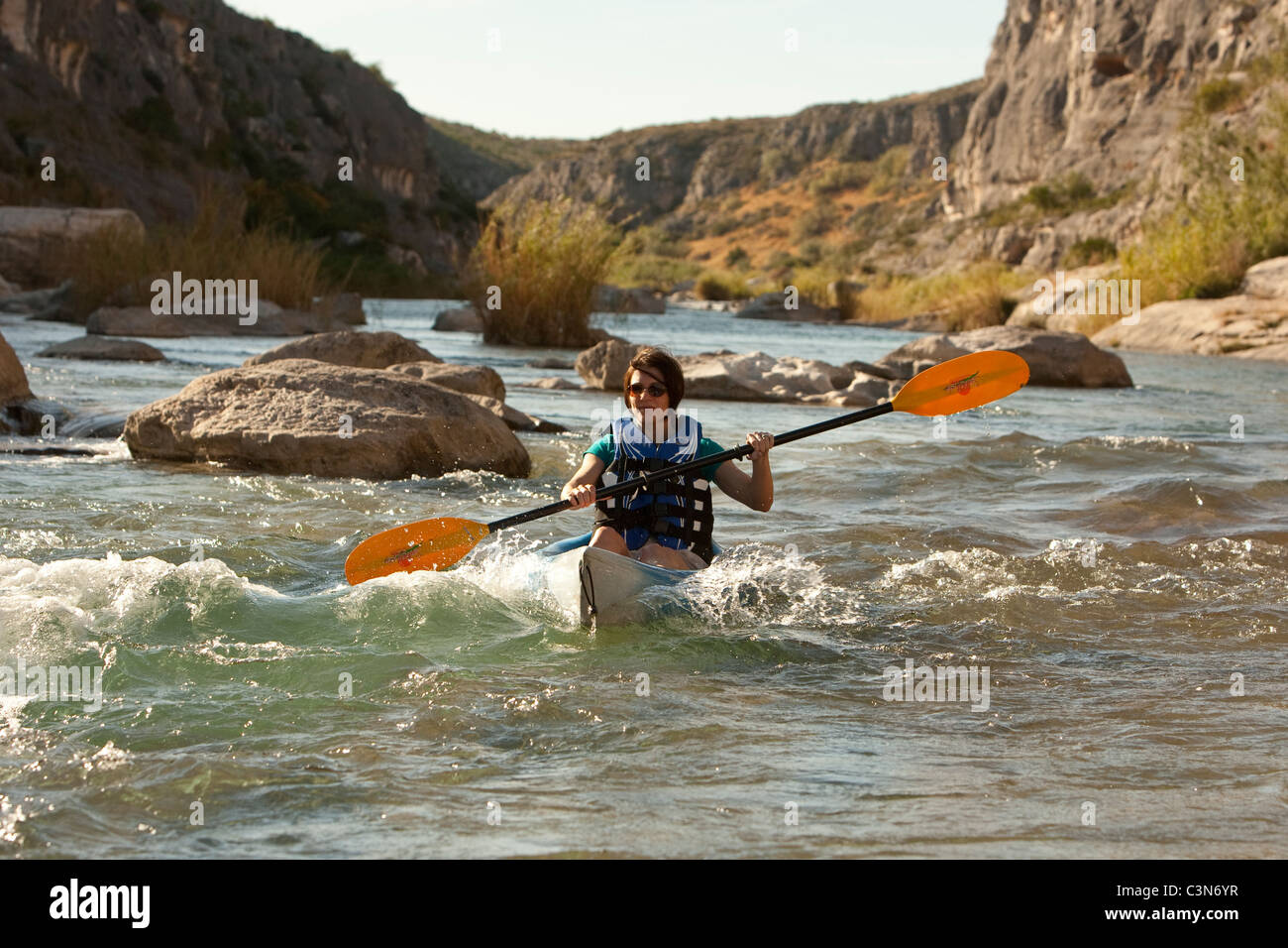 Femmina pale kayaker giù rapide sul fiume Pecos nella parte sud-ovest della Val Verde County, Texas. Foto Stock