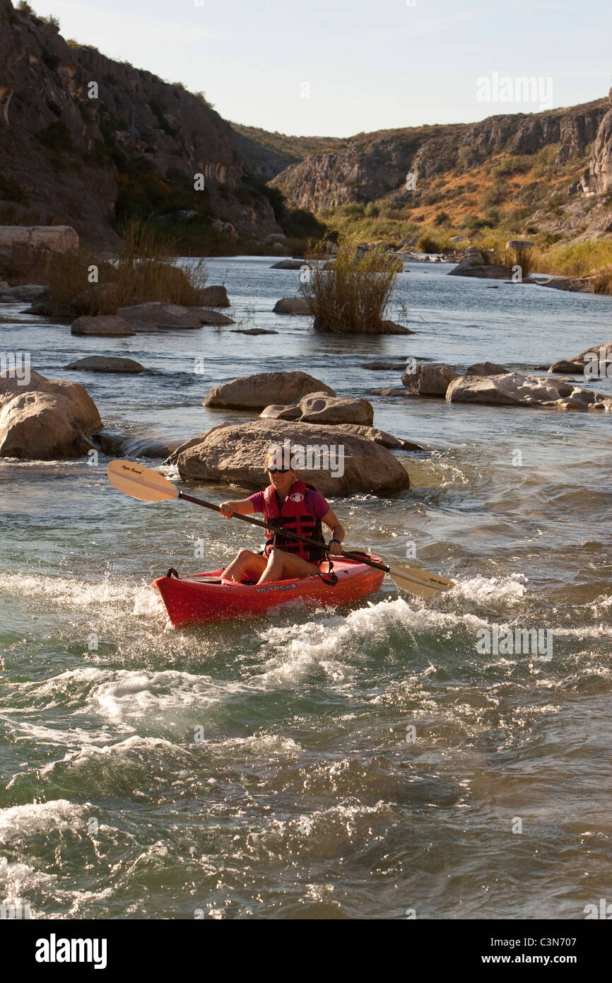 Femmina pale kayaker giù rapide sul fiume Pecos nella parte sud-ovest della Val Verde County, Texas. Foto Stock