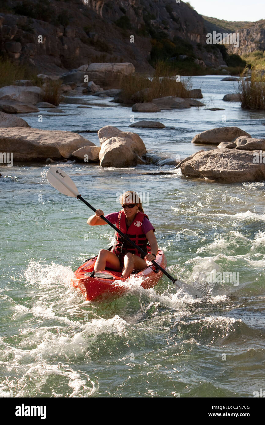 Femmina pale kayaker giù rapide sul fiume Pecos nella parte sud-ovest della Val Verde County, Texas. Foto Stock