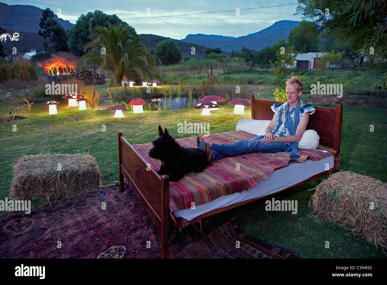 Barrydale MacPie homefineware e lampadari e designer designer Sean Daniel rilassante con il suo cane su un letto nel suo giardino Foto Stock