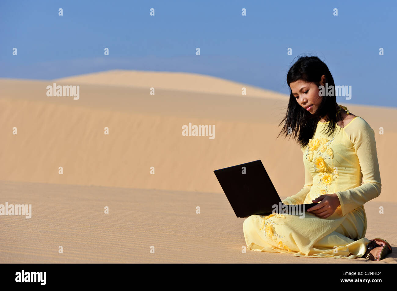 Giovane donna asiatica con un laptop in Dune Foto Stock
