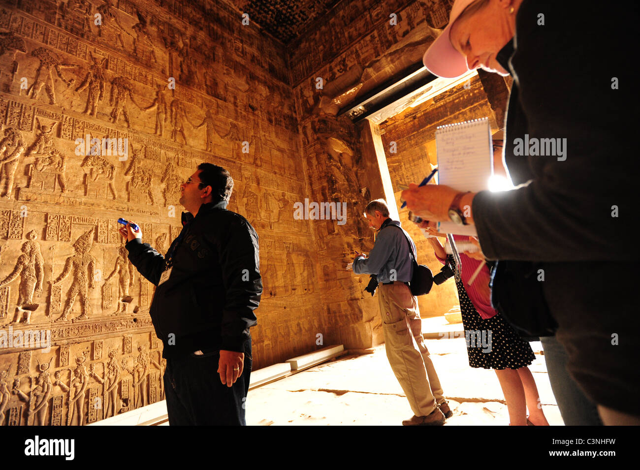 Africa Medio Oriente Egitto tempio di Dendara - una guida mostra ai visitatori i dettagli del bassorilievo incisioni su una parete del tempio Foto Stock